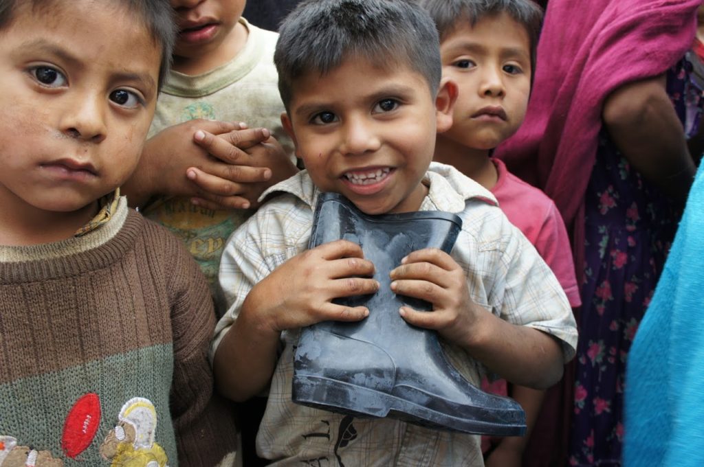 Niños abrigados con cobertores entregados por la organización